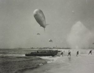 Carrabelle Beach with military landing craft and soldiers running with explosions behind them
