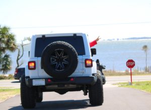 White jeep driving down a driveway