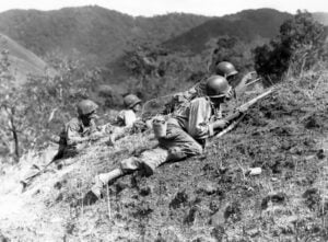 Four WWII soldiers lay on a hill